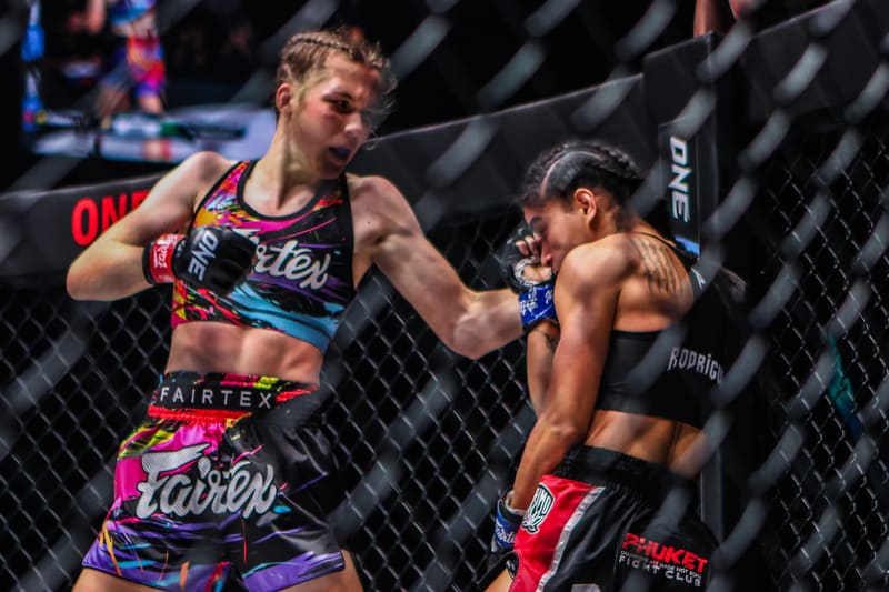 Smilla Sundell trading punches with an opponent through the cage fence during a ONE Championship fight