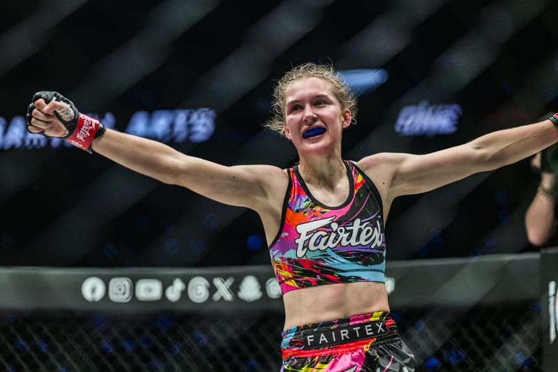 Smilla Sundell celebrating with arms raised inside the cage in a Fairtex crop top