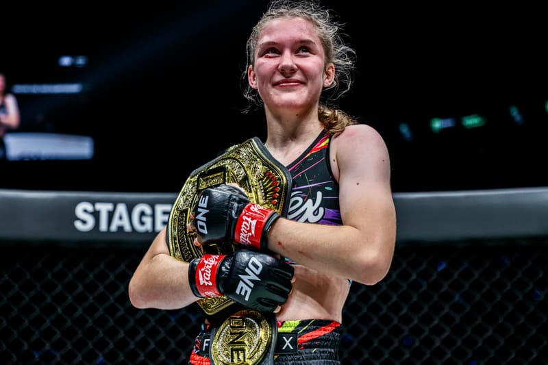 Smilla Sundell smiling and holding the ONE Championship belt on stage after a win