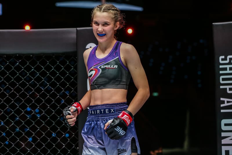 Smilla Sundell smiling with a blue mouthguard in after a fight, wearing a purple Fairtex fight kit