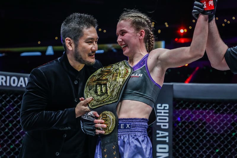 Smilla Sundell smiling next to an official as she is presented with the ONE Championship belt