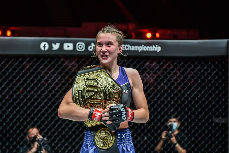 Smilla Sundell holding the ONE Championship belt to her chest, smiling for photographers