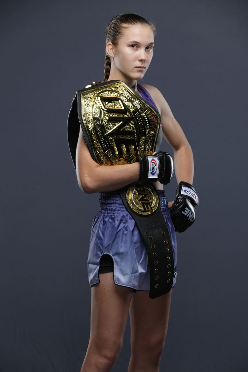 Studio portrait of Smilla Sundell wearing the ONE Championship belt over one shoulder in purple Fairtex shorts