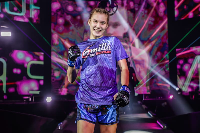 Smilla Sundell smiling and giving a thumbs up on stage before a fight in a blue walkout jersey