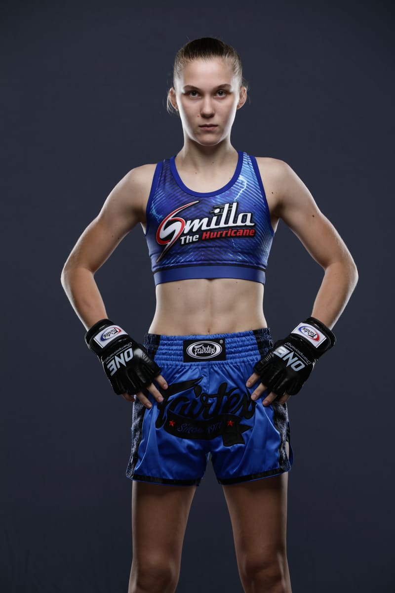 Studio portrait of Smilla Sundell standing with hands on hips in a blue "Smilla The Hurricane" fight kit