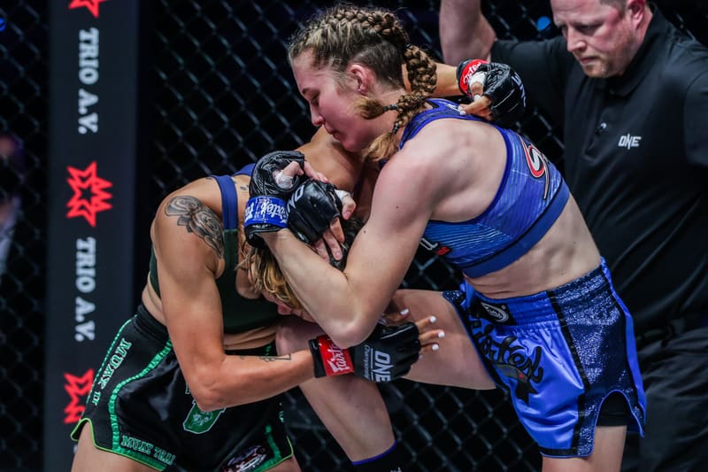 Smilla Sundell clinching with an opponent against the cage during a fight