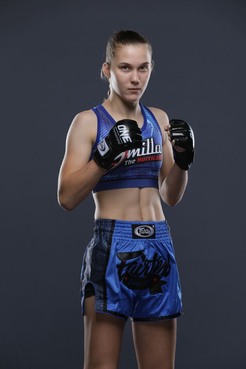 Studio portrait of Smilla Sundell standing with both gloves raised in a guard, in a blue "Smilla The Hurricane" top and blue Fairtex shorts
